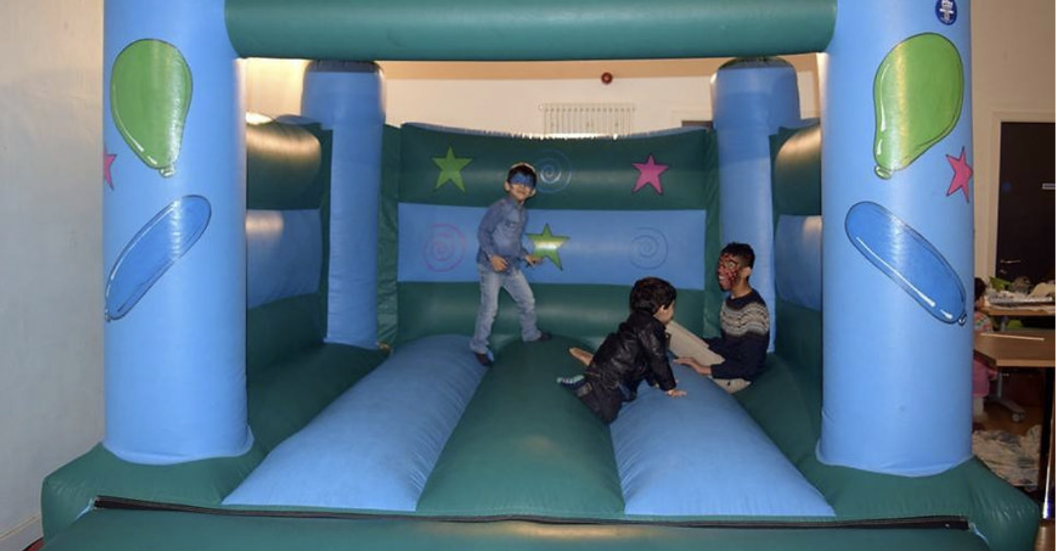 Three children playing on a bouncy castle.